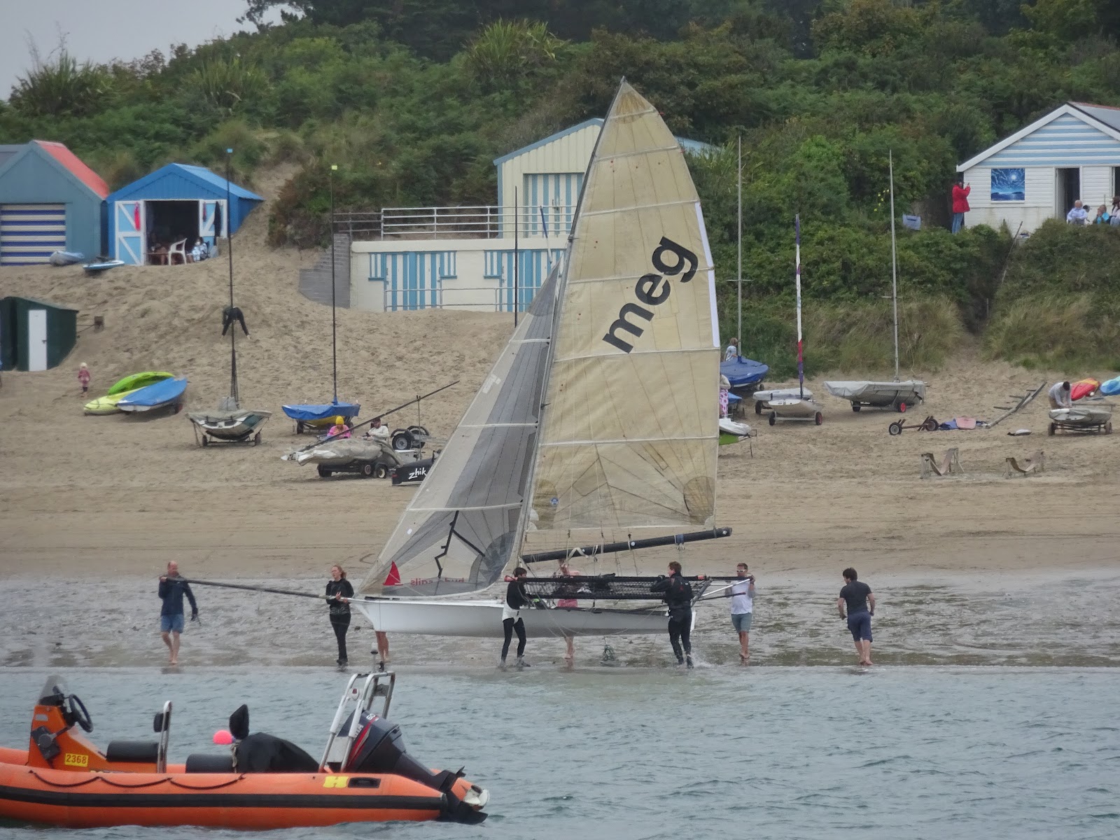 Beomus in the shallows off a beach, her crew walking her out on the wings